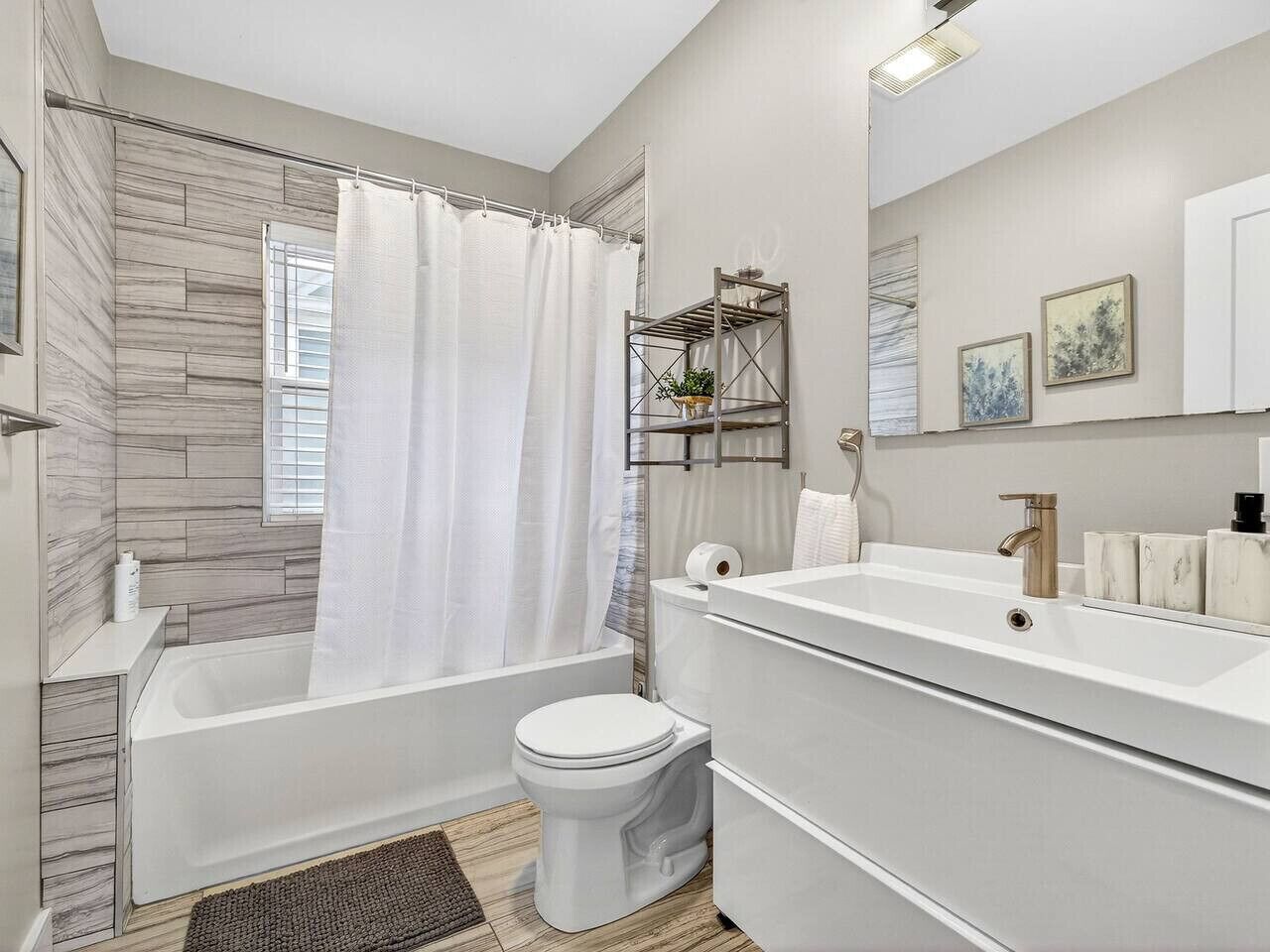 Une salle de bain moderne équipée d’une baignoire, de toilettes et d’un meuble-lavabo.