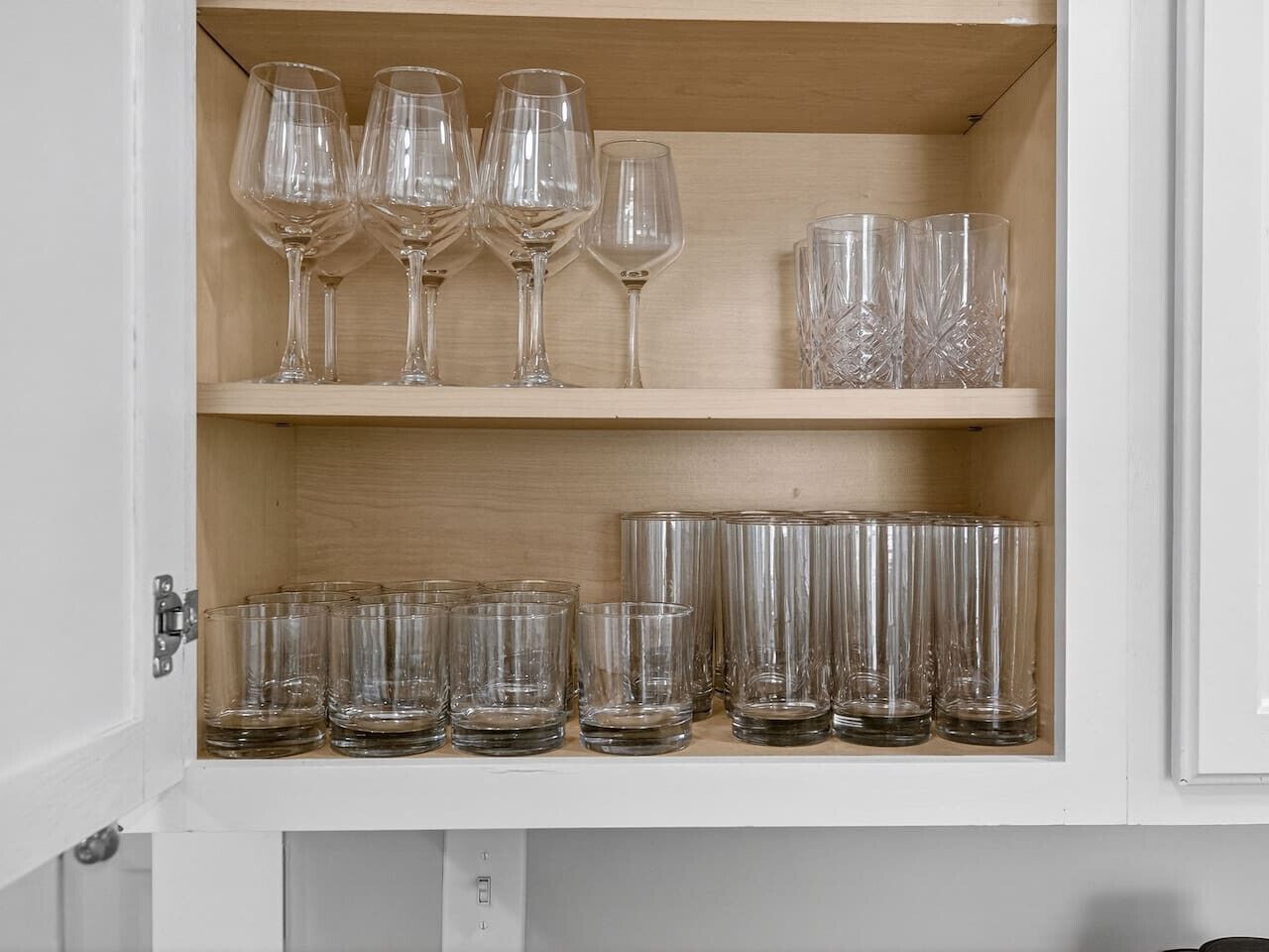 A cabinet with two shelves containing various glassware.