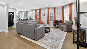 Ein modernes Wohnzimmer mit einem grauen Sofa, einem Couchtisch und einem gemusterten Teppich.