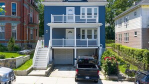 A two-story residential building with a front garage, a balcony, and a satellite dish.