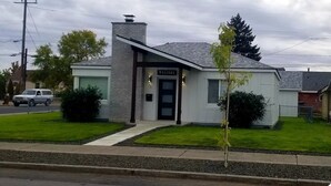 Un edificio pequeño de una sola planta con un letrero que dice 'WELCOME', una chimenea y un césped bien cuidado.
