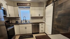 Una cocina moderna con armarios blancos, electrodomésticos de acero inoxidable y una puerta corredera estilo granero.