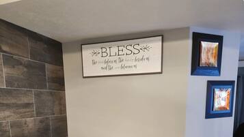 Un comedor con una mesa y sillas de madera, un letrero en la pared y obras de arte enmarcadas.