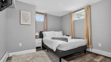 A bedroom with a bed, nightstand, and a window with curtains.
