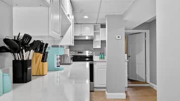 A modern kitchen with white cabinets, a stainless steel refrigerator, and a countertop with kitchen utensils.