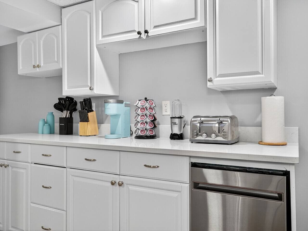 A kitchen with white cabinets, a coffee maker, a toaster, and a dishwasher.