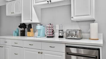 A kitchen with white cabinets, a coffee maker, a toaster, and a dishwasher.