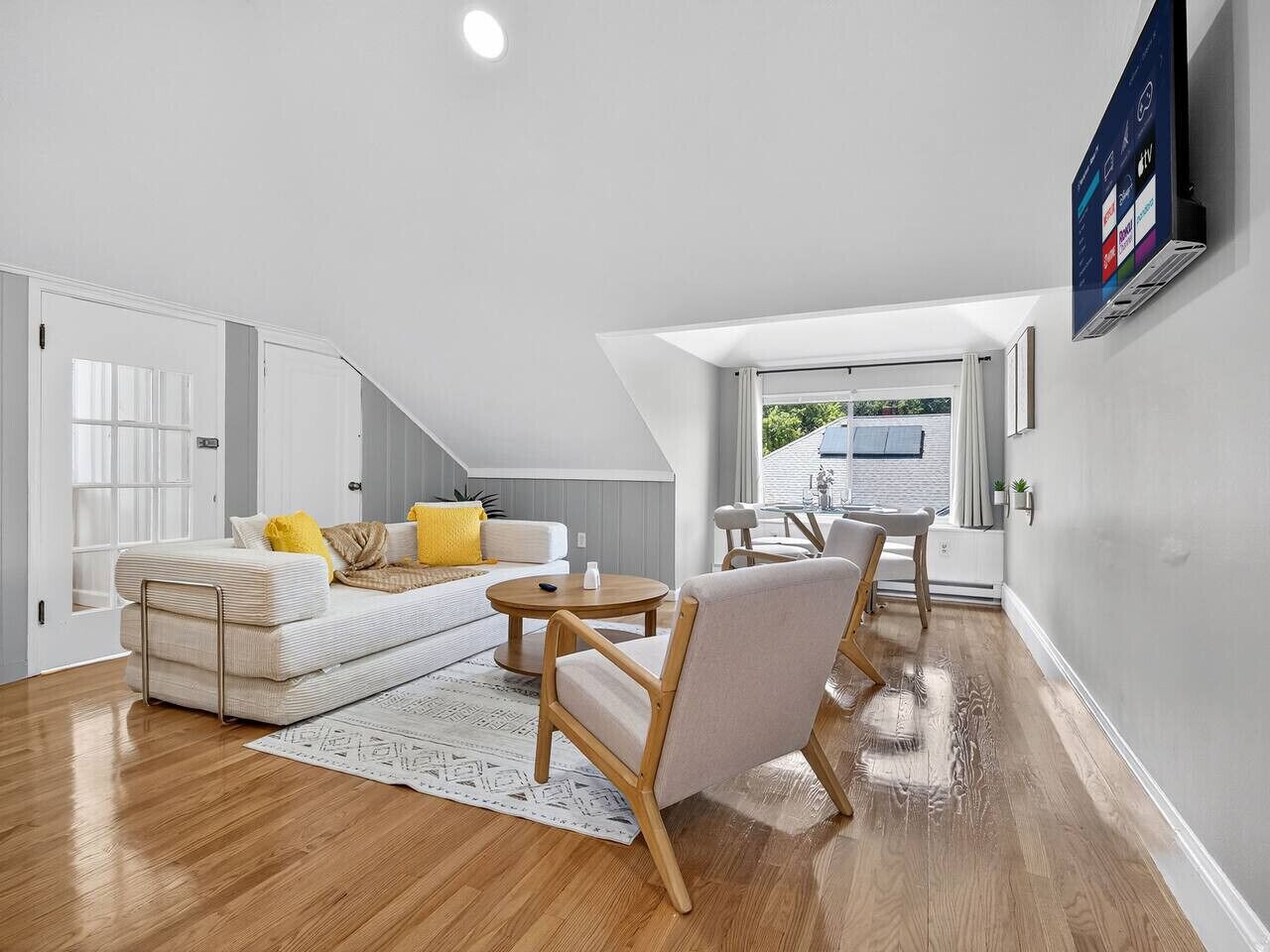 A modern living room with a sofa, armchairs, a coffee table, and a TV mounted on the wall.