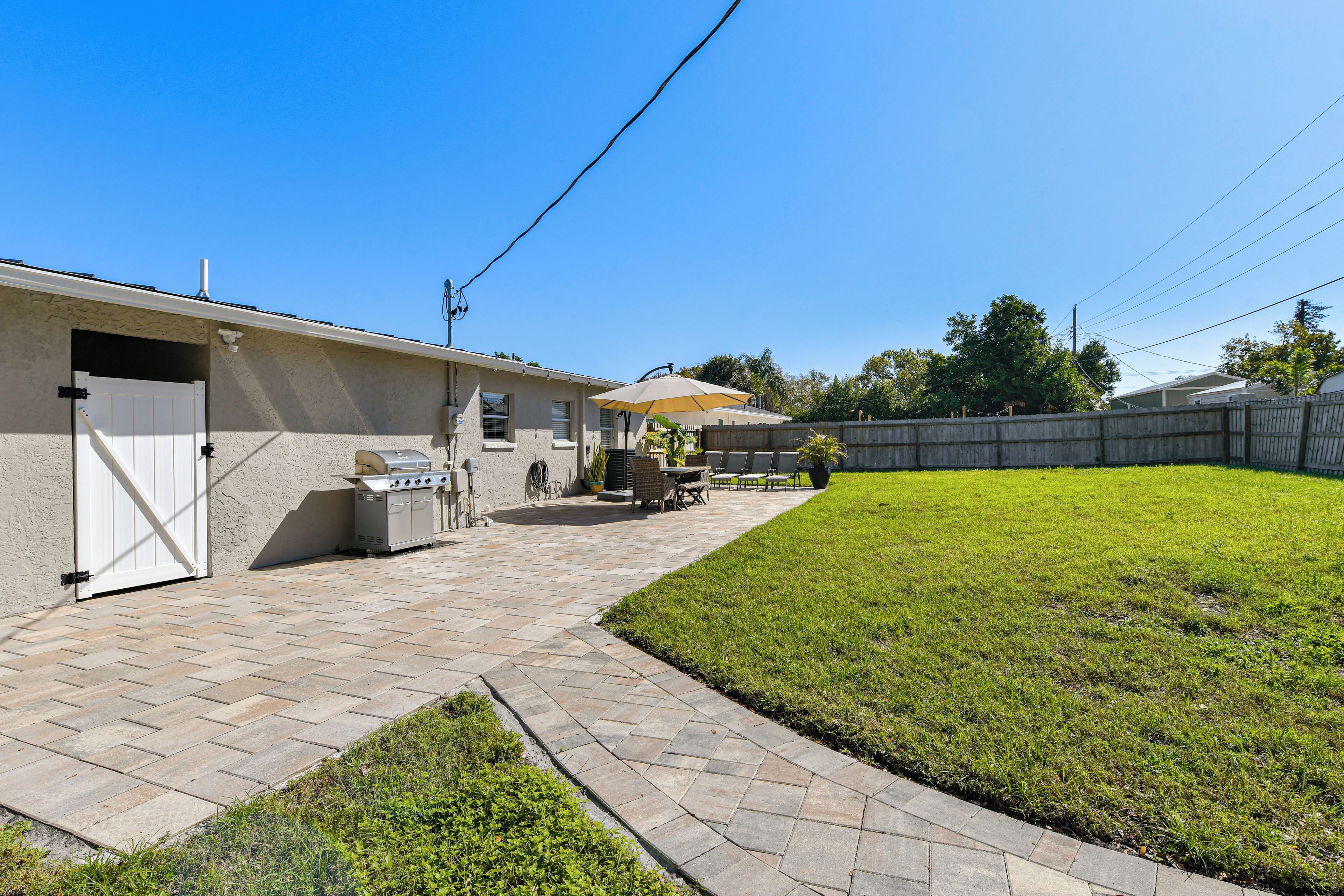 A backyard with a barbecue grill, patio furniture, and a wooden fence.