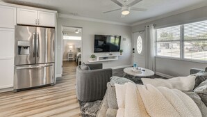 A modern kitchen with a built-in refrigerator, a dining area with a round table, and a living room with a gray sofa and a flat-screen TV. - 5 Mi to Riverwalk: Bradenton Family Home w/ Yard (Bradenton)
