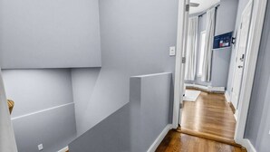 Un pasillo con suelo de madera, paredes grises y una puerta al final.