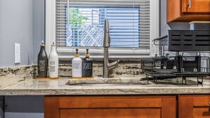 Cocina con encimera de granito, grifo de acero inoxidable y armarios de madera.