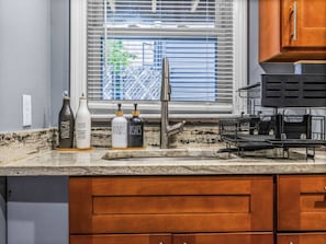 A kitchen with a granite countertop, a stainless steel faucet, and wooden cabinets. - Historic 2 floor Apt in Boston w/ outdoor deck! (Boston)