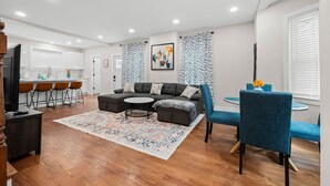 Un salon moderne avec un canapé d’angle, une table basse ronde et un fauteuil bleu.
