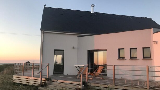 Un bâtiment moderne à deux étages, doté d’un toit plat, d’un balcon avec une balustrade et d’une porte donnant sur l’intérieur.