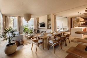 A spacious living area with a dining table, comfortable seating, and a large window offering a view of greenery. - Villa Ka'an Pura Selva luxury and nature near the beach (Tulum)