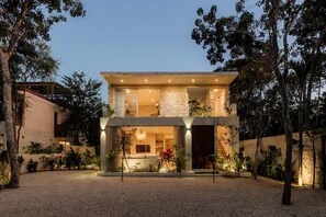A two-story house with a stone facade, a balcony, and a well-lit interior. - Villa Ka'an Pura Selva luxury and nature near the beach (Tulum)