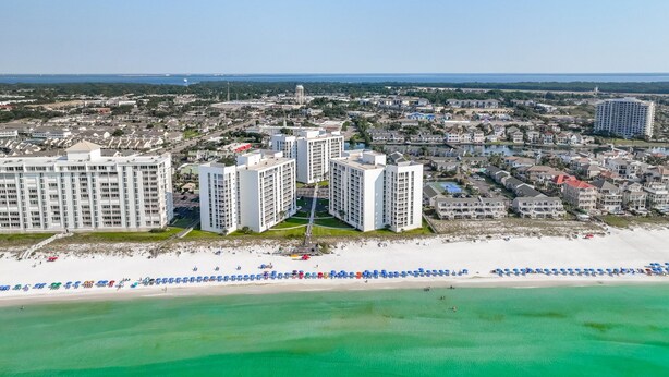 A coastal cityscape with high-rise buildings, a beach with umbrellas, and a clear view of the ocean. - Shoreline Towers 3023 -seasonal beach service pool-near beach (Destin)
