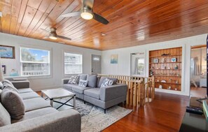 Ein geräumiges Wohnzimmer mit grauem Sofa, Holzboden und einer Bücherwand.