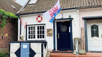 Ein Haus mit einer blauen Tür, einer weißen Wand und einer Flagge.