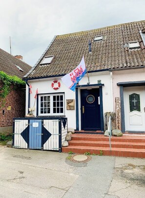 Ein Haus mit einer blauen Tür, einer weißen Wand und einer Flagge.
