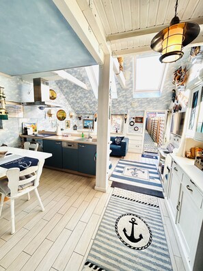 Cocina temática náutica con comedor, vista a través de un ventanal y techo con diseño de nubes.