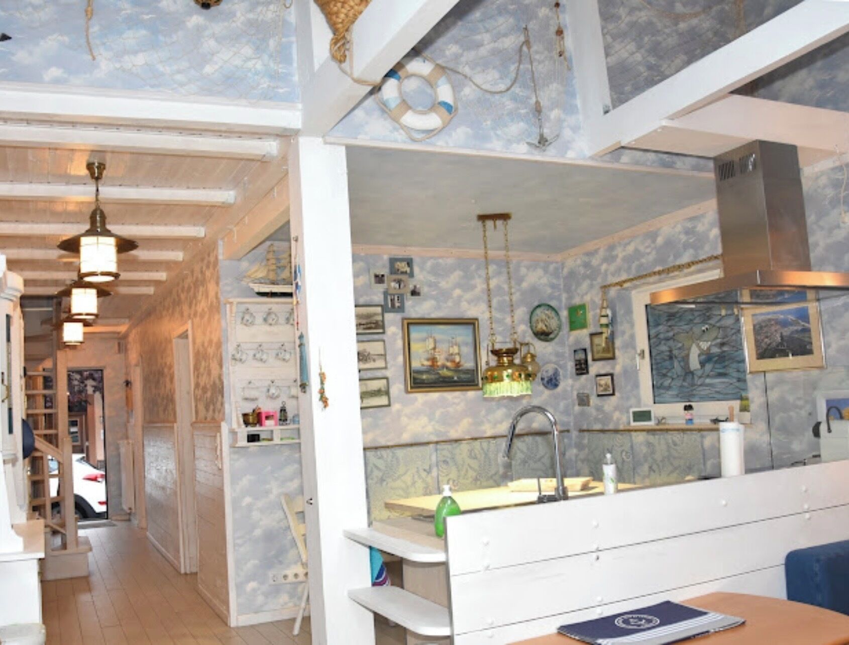 A room with a kitchen area, a dining table, and a hallway leading to another room.