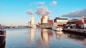 Un puerto con barcos, un edificio alto y un edificio rojo con un letrero.