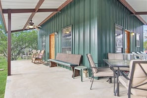 An outdoor patio with a covered seating area, including a table and chairs, and a wooden bench. - Cherry Creek Cabin | Near Garner | Frio | Concan (Concan)