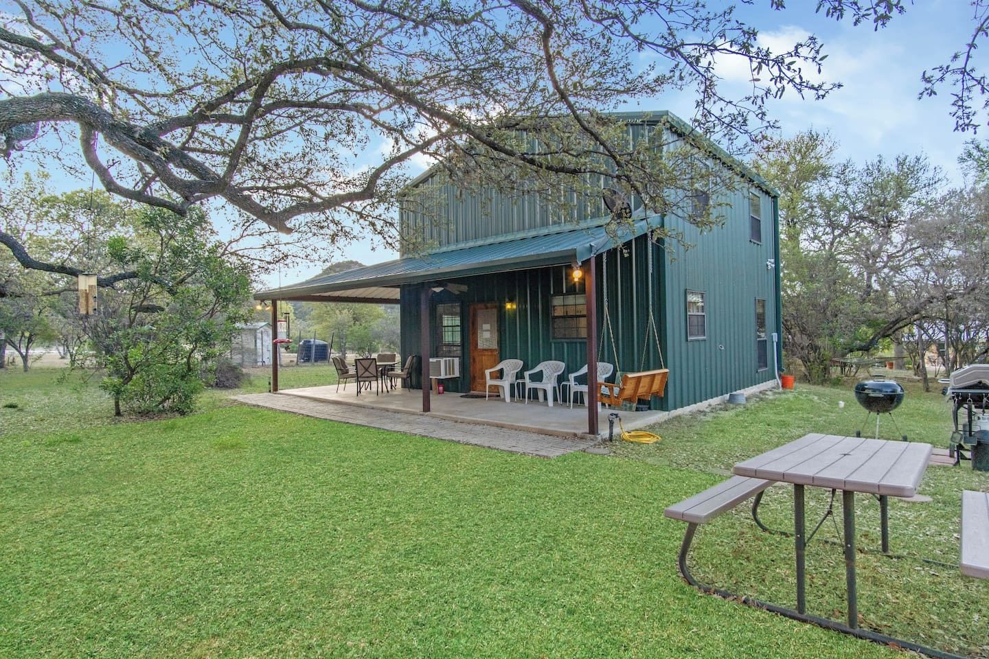 A rustic cabin with a covered patio, outdoor seating, and a barbecue area.