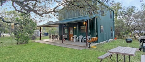 A rustic cabin with a covered patio, outdoor seating, and a barbecue area.