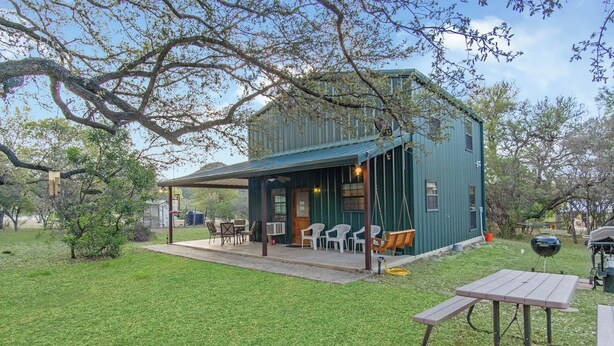 Eine rustikale Holzhütte mit überdachter Terrasse, Sitzgelegenheiten im Freien und Grillplatz.