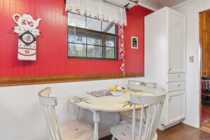 Un comedor con una mesa y sillas, un ventanal con vistas y un armario blanco.