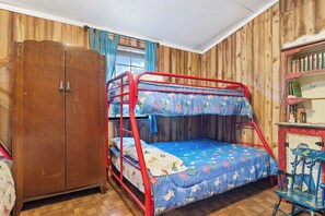 A bunk bed with a red frame and blue bedding, a wooden wardrobe, and a small desk with a chair. - Cherry Creek Cabin | Near Garner | Frio | Concan (Concan)