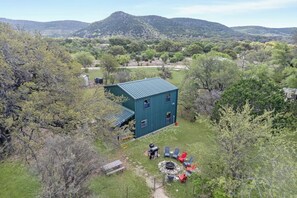 Un bâtiment écologique doté d’un toit en métal, entouré d’arbres et d’une pelouse aménagée avec des espaces de détente en plein air.