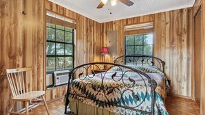 Ein Zimmer mit Holzwänden, einem Bett, einem Sessel und einem Deckenventilator.