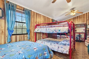 A bunk bed room with a wooden wall, a ceiling fan, and a bookshelf. - Cherry Creek Cabin | Near Garner | Frio | Concan (Concan)