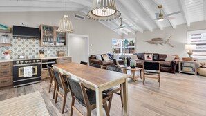 Ein großzügiger Wohnbereich mit Holztisch, Ledersofas und einer hohen Decke mit sichtbaren Balken.