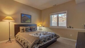 A bedroom with a bed, a floor lamp, a window, and a painting on the wall. - Walk To Skiing, Quiet Neighborhood, Big House (Steamboat Springs)