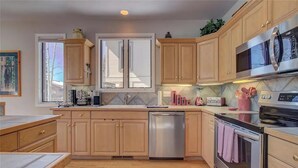 A modern kitchen with wooden cabinets, stainless steel appliances, and a dishwasher. - Walk To Skiing, Quiet Neighborhood, Big House (Steamboat Springs)