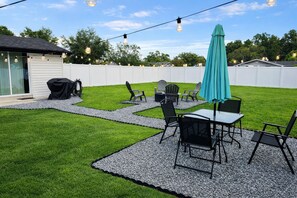 Ein Garten mit einer Terrassenfläche, Gartenmöbeln und Lichterketten.