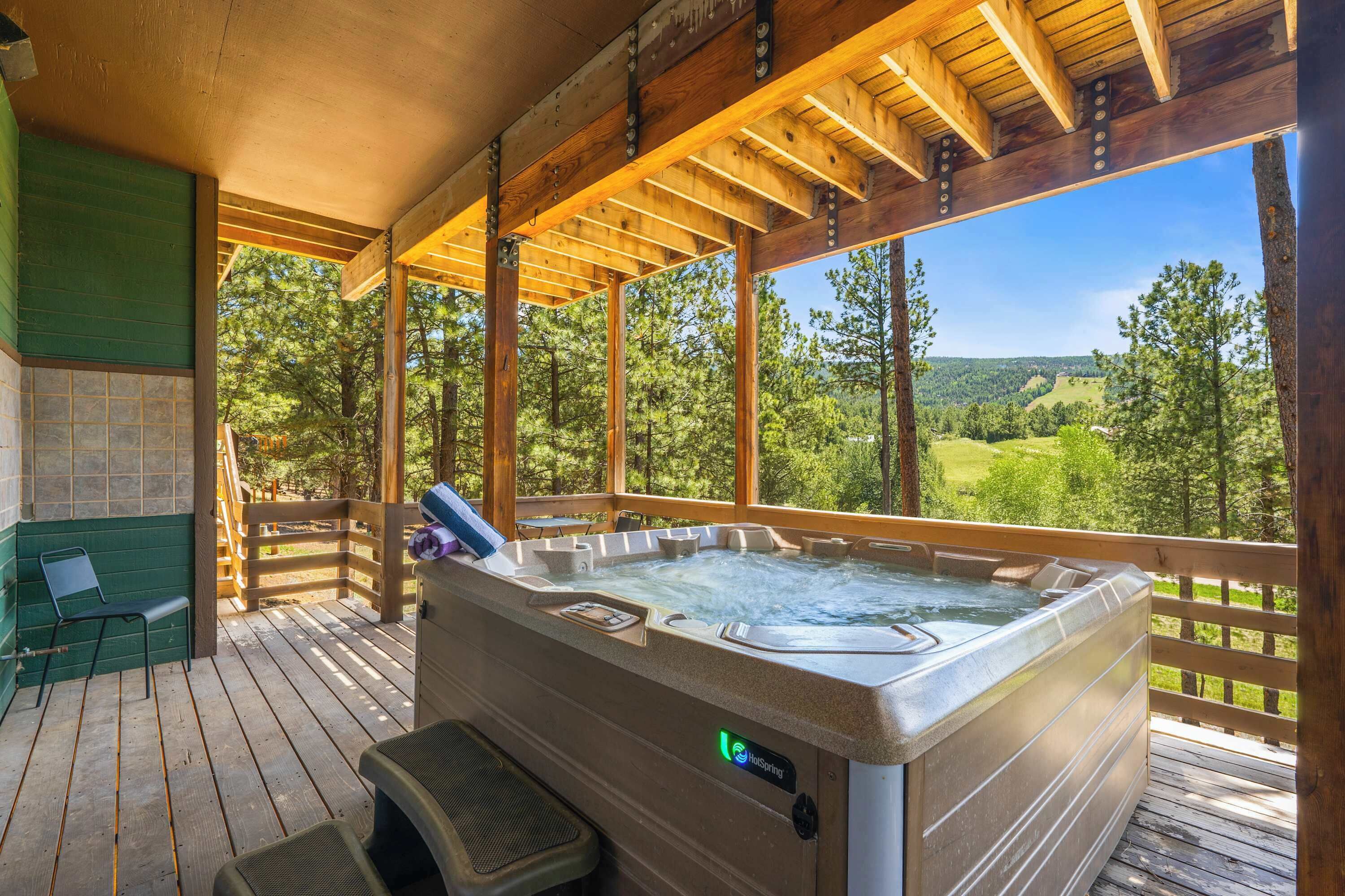 A hot tub on a wooden deck with a view of a green landscape.