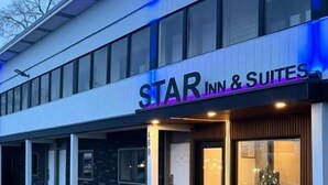 A hotel named 'STAR INN & SUITES' with a modern facade, large windows, and a parking lot with marked spaces. - Star Inn & Suites (Chicago Heights)