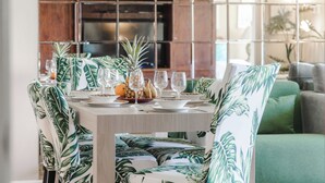 A dining area with a table set for four, surrounded by chairs with a tropical leaf pattern. - 🌅 Maui Magic! Panoramic Beachfront Stay! Ocean Views, Pool, Hot Tub, Sleeps 8🌊 (Kihei)