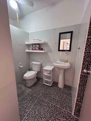 Et badeværelse med toilet, håndvask og hylder.