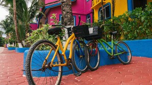 A bicycle parked next to a colorful building with a blue base and a red brick pathway. - Rooftop small pool | El Segundo (Puerto Morelos)