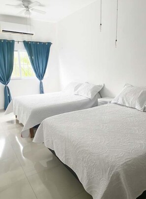 A room with two beds, a ceiling fan, and a window with curtains. - Rooftop small pool | 5 minutes access beach (Puerto Morelos)