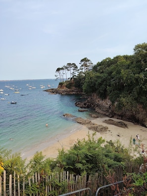 A coastal beach with boats, a rocky shoreline, and dense greenery. - Charming T2 apartment opposite the beach, with swimming pool, sauna, parking and small sea view. (Plougonvelin)