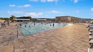 Zona de piscina con suelo de baldosas, una escalera de acceso y sillas de descanso.