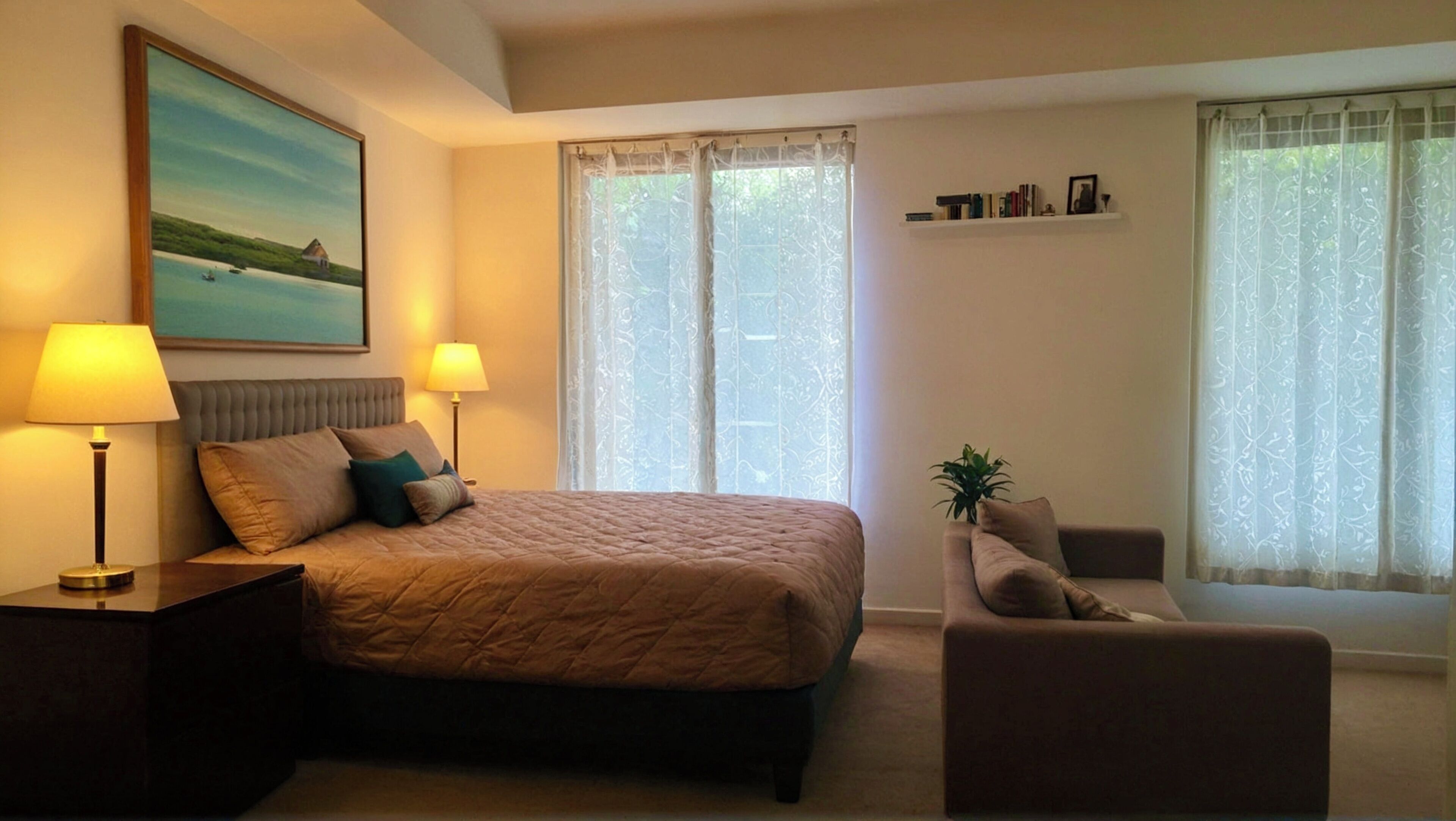 Ein Schlafzimmer mit einem Bett, zwei Nachttischen mit Lampen, einem Sessel, einer Zimmerpflanze und einem Bild an der Wand.